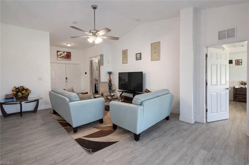 A living room features light blue sofas, a patterned area rug, and wood-look tile flooring — 2917 12TH STREET SW, LEHIGH ACRES, FL
