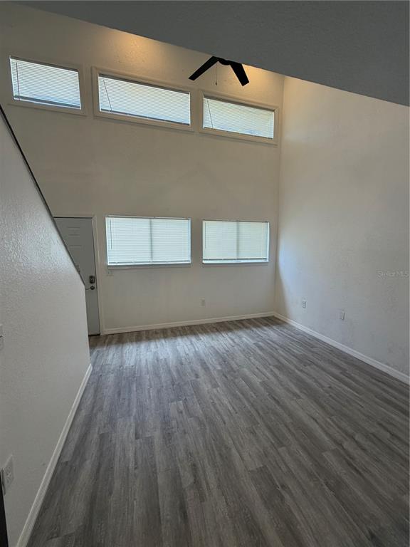 A room with high ceilings, grey wood-look flooring, and multiple windows with blinds — 3924 CRAYRICH CIRCLE UNIT C5, ORLANDO, FL