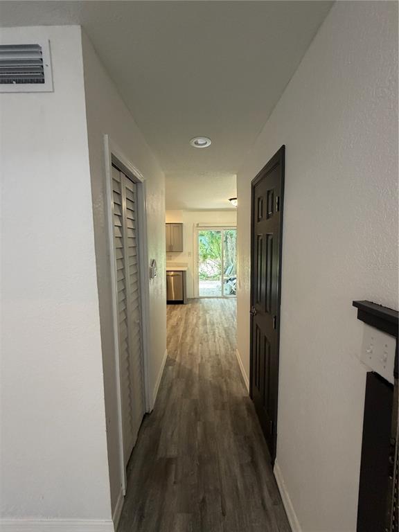 A hallway with wood-look flooring leads toward a kitchen and a sliding glass door — 3924 CRAYRICH CIRCLE UNIT C5, ORLANDO, FL