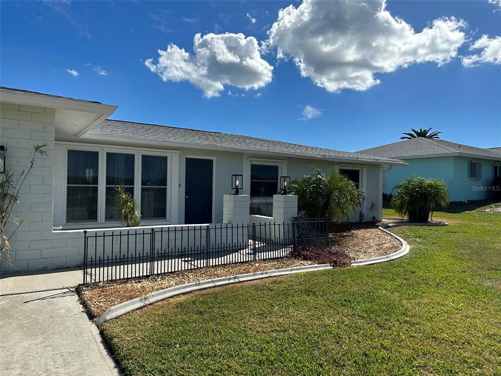The exterior of a light-colored house features a small front patio enclosed by black fencing — 45 OAKLAND HILLS COURT, ROTONDA WEST, FL