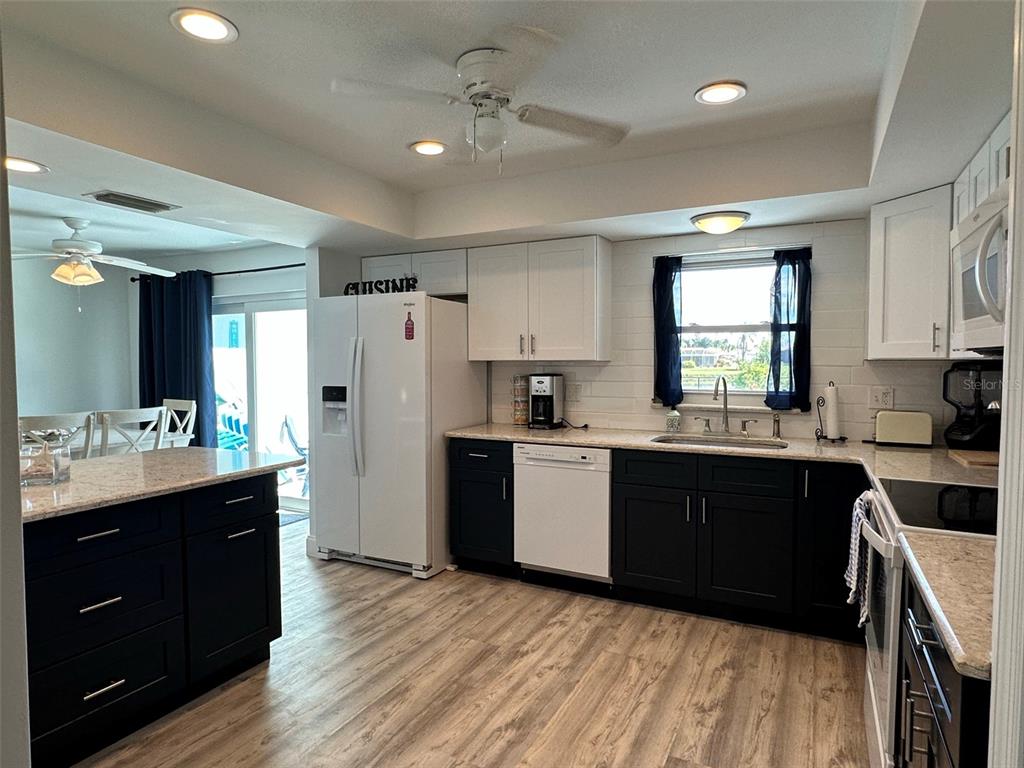 A kitchen with dark lower cabinets, white upper cabinets, light countertops, and wood-look flooring — 45 OAKLAND HILLS COURT, ROTONDA WEST, FL