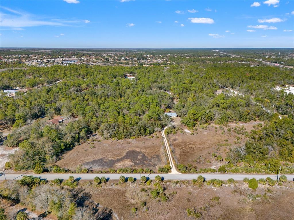 An aerial view shows a house set back from a road behind a large lot — LONG LAKE AVENUE, WEEKI WACHEE, FL