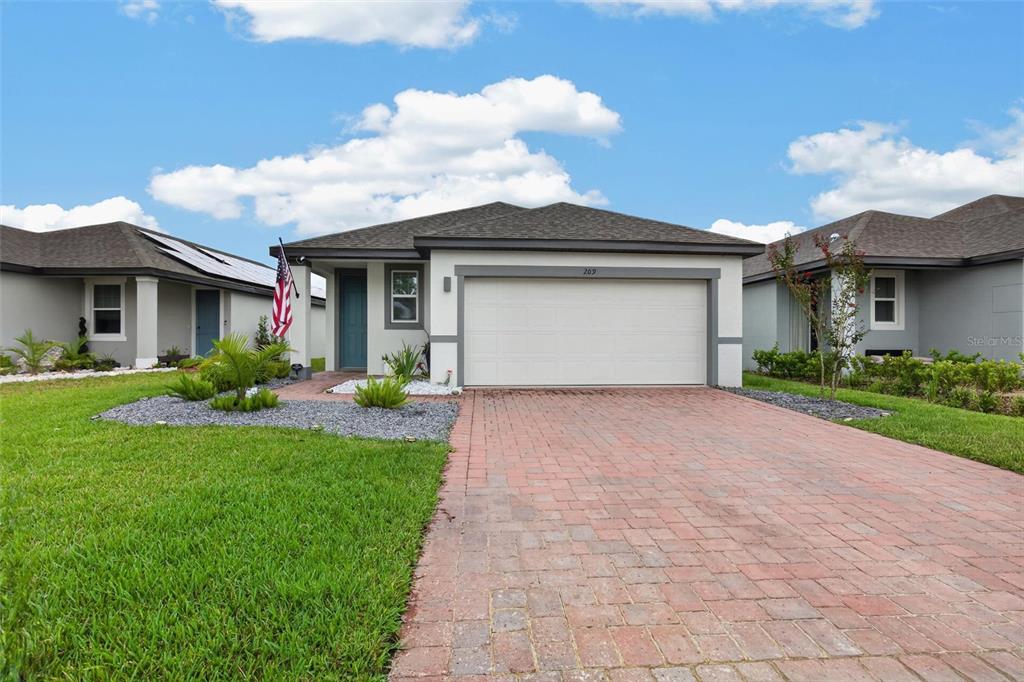 A single-story house with a brick driveway, a two-car garage, and a front yard — 209 LINKS TERRACE BOULEVARD, DAYTONA BEACH, FL