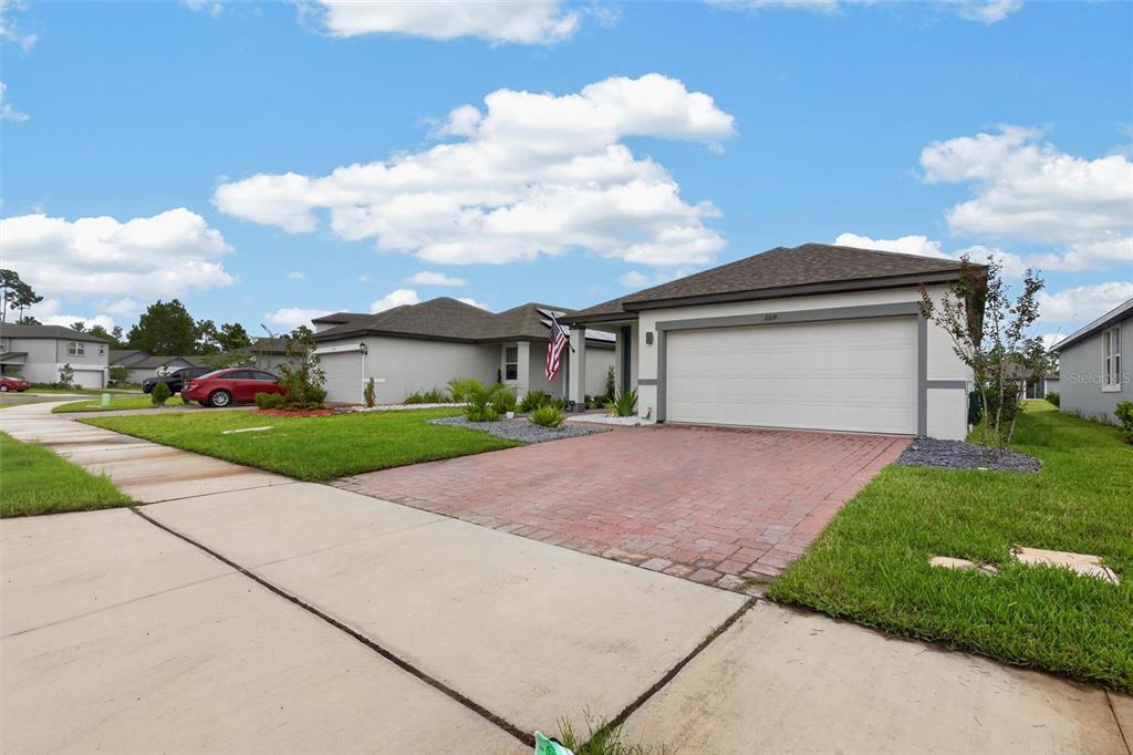 A single-story suburban house with a brick paver driveway and a two-car garage — 209 LINKS TERRACE BOULEVARD, DAYTONA BEACH, FL