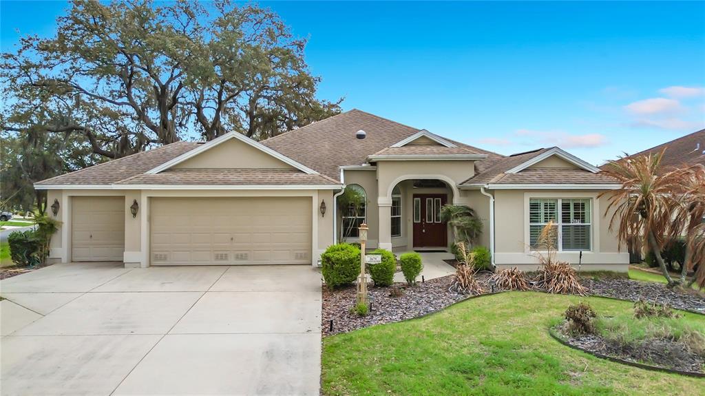 A single-story house with a beige stucco exterior, a three-car garage, and a tiled roof — 2679 LANTANA AVENUE, THE VILLAGES, FL