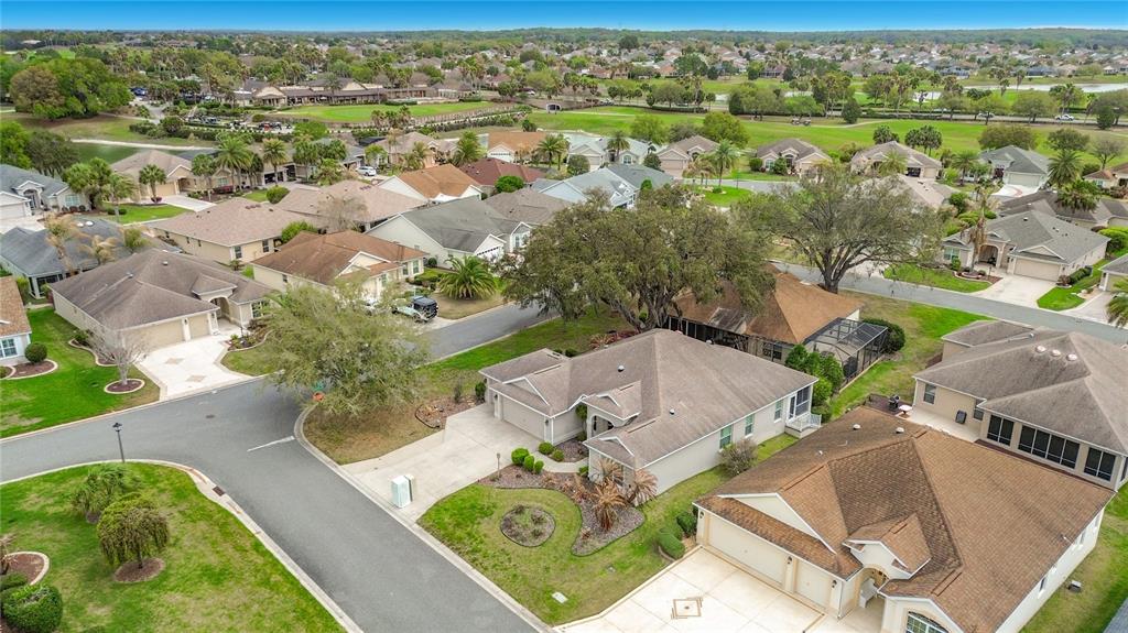 An aerial view of a suburban neighborhood featuring single-family homes, paved streets, and green lawns — 2679 LANTANA AVENUE, THE VILLAGES, FL