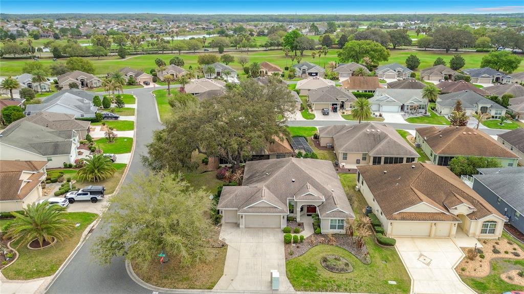 An aerial view shows a suburban neighborhood with single-family homes, paved streets, and green lawns — 2679 LANTANA AVENUE, THE VILLAGES, FL