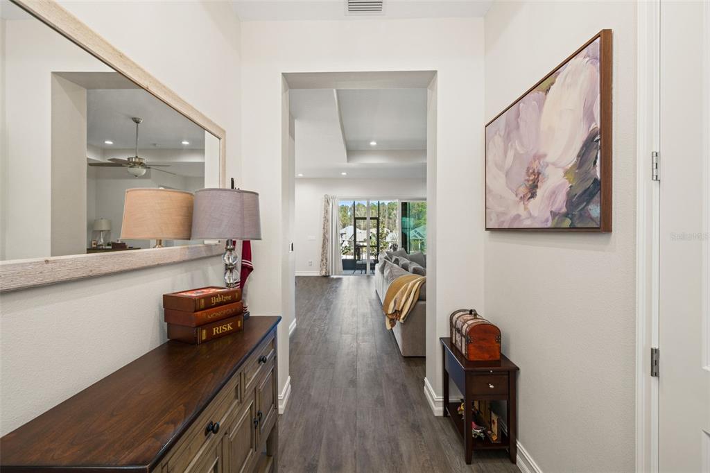 A hallway with wood-look flooring leads to a living room with a view of the outdoors — 4698 HICKORY OAK DRIVE, BROOKSVILLE, FL
