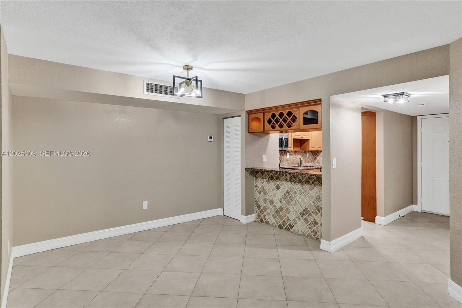 A dining area features tile flooring, a breakfast bar with decorative tile, and overhead lighting — 927 NE 199th St # 103, Miami FL 33179, MIAMI, FL