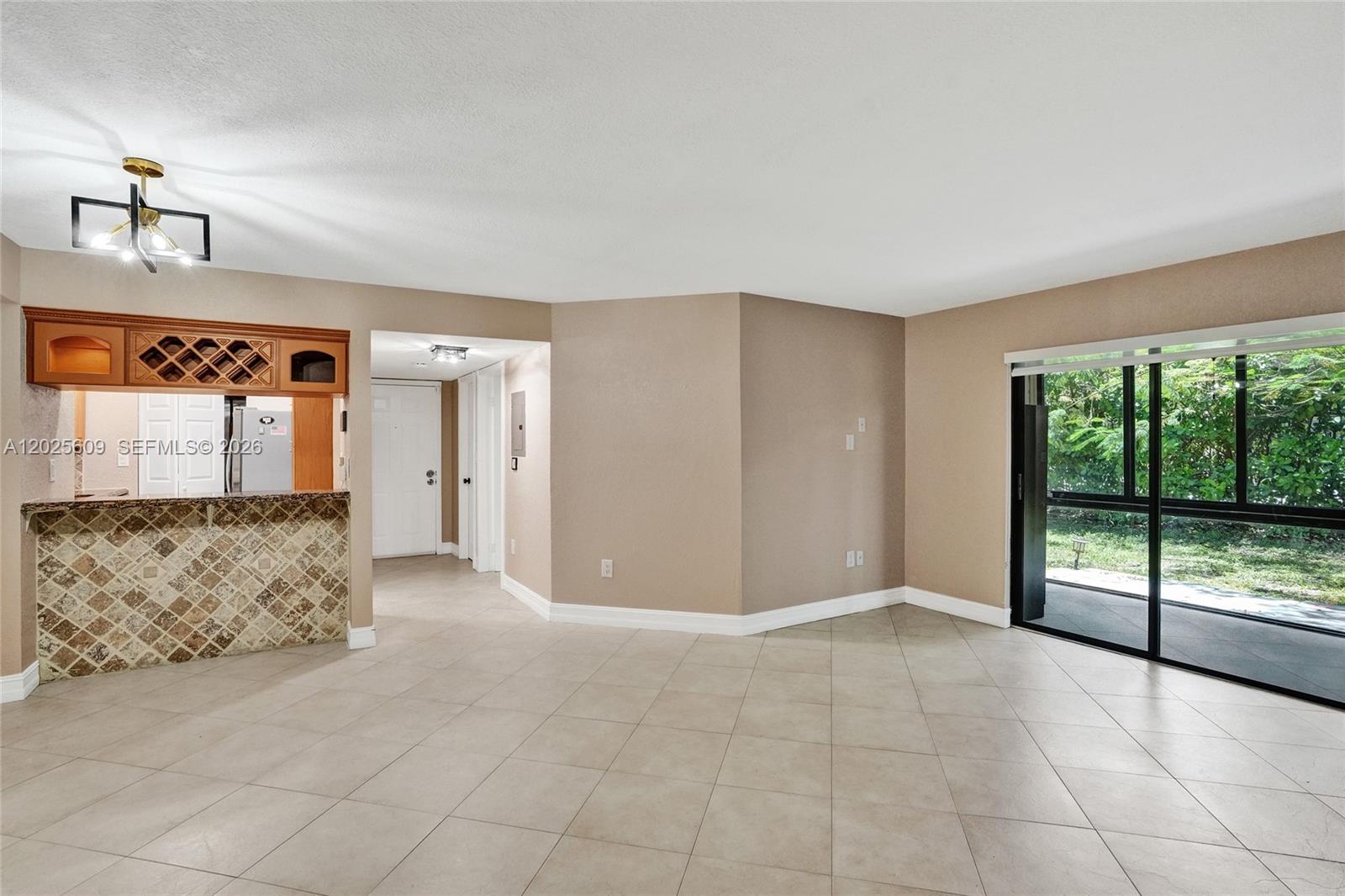 An open living area features tile floors, a kitchen pass-through, and sliding glass doors — 927 NE 199th St # 103, Miami FL 33179, MIAMI, FL