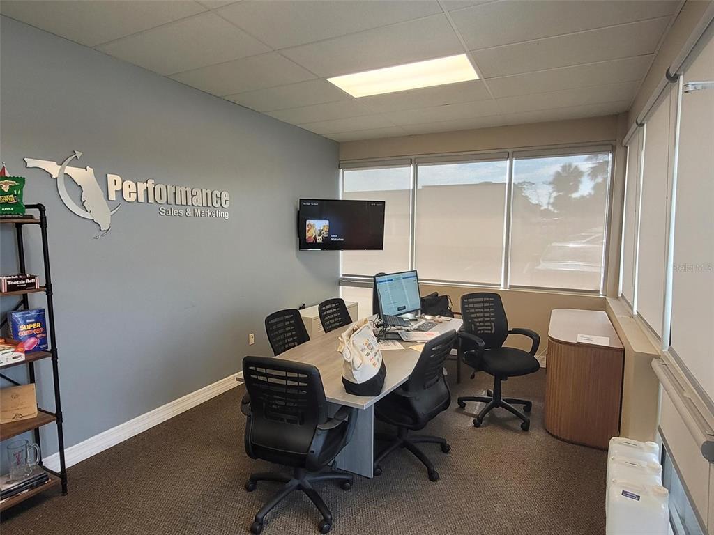 An office space features a conference table, four chairs, a wall-mounted television, and company signage — 5404 HOOVER BOULEVARD UNIT 5, TAMPA, FL