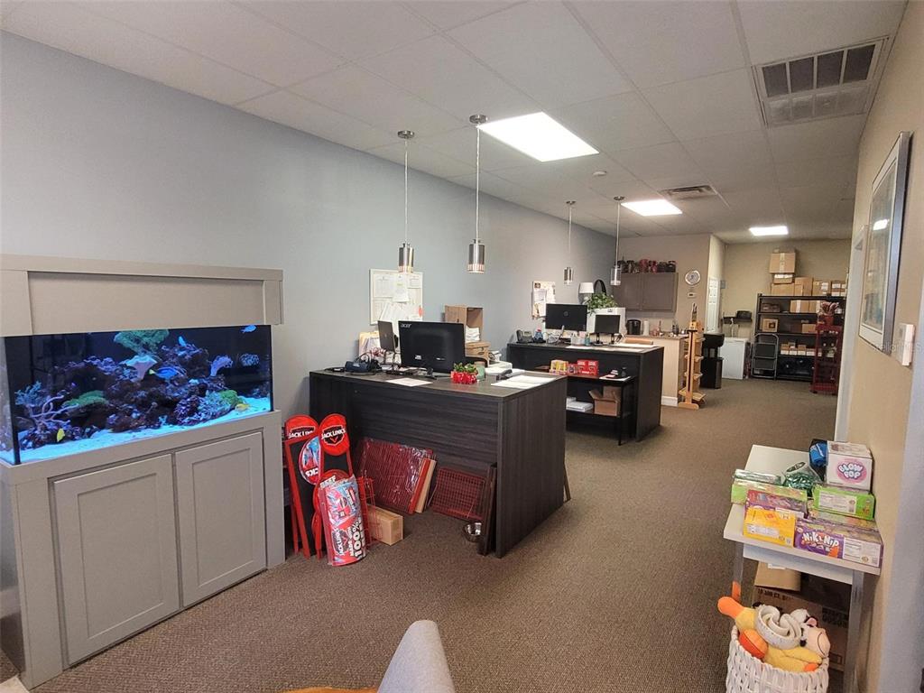 An office space features a large aquarium, two desks, and shelving units on carpeted floors — 5404 HOOVER BOULEVARD UNIT 5, TAMPA, FL