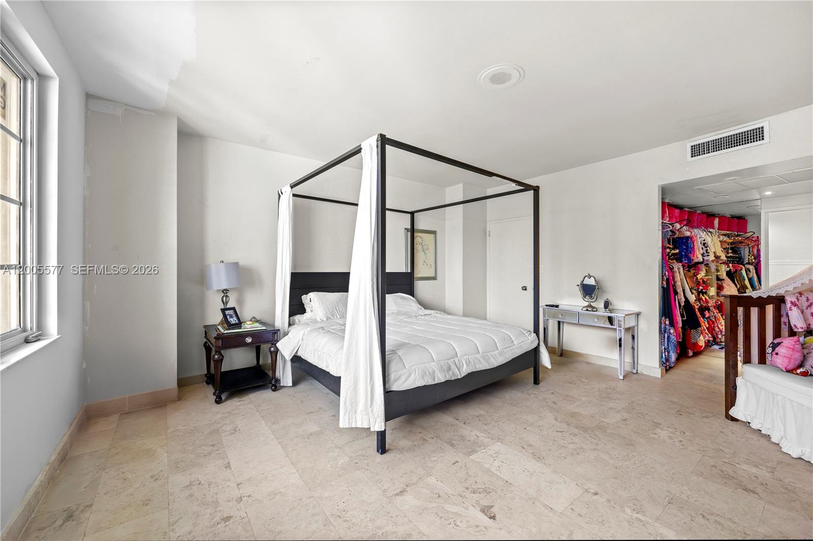 A bedroom features a four-poster bed, tile flooring, and an open walk-in closet — 5255 Collins Ave # 11A, Miami Beach FL 33140, MIAMI BEACH, FL