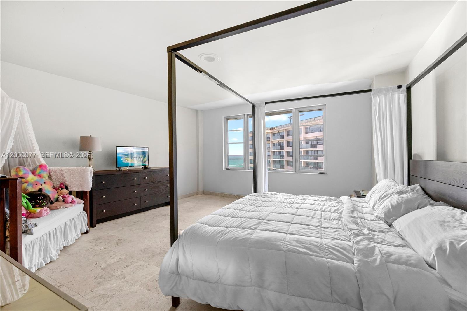 A bedroom features a four-poster bed, a dresser with a television, and a small daybed — 5255 Collins Ave # 11A, Miami Beach FL 33140, MIAMI BEACH, FL