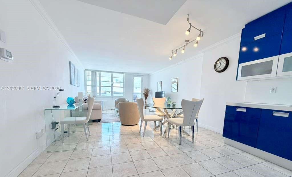 A bright, open-concept living and dining area features white tile floors and blue cabinetry — 100 Lincoln Rd # 1423, Miami Beach FL 33139, MIAMI BEACH, FL