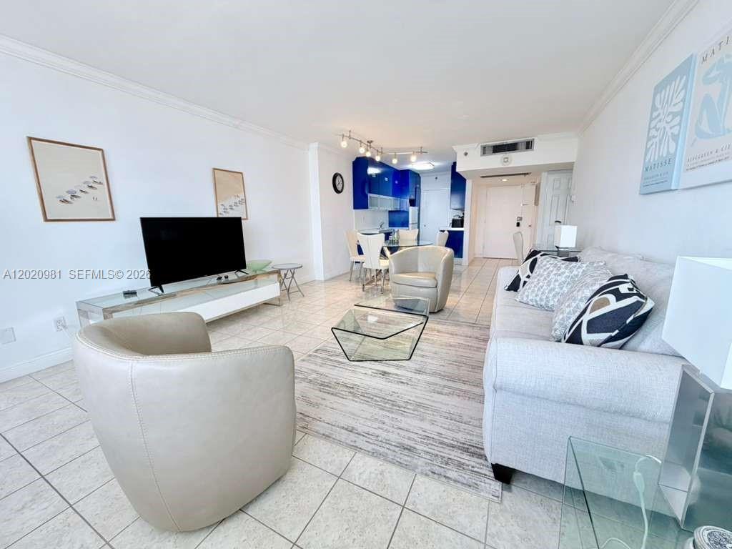 A living room features tile floors, a white sofa, two armchairs, and a blue kitchen — 100 Lincoln Rd # 1423, Miami Beach FL 33139, MIAMI BEACH, FL