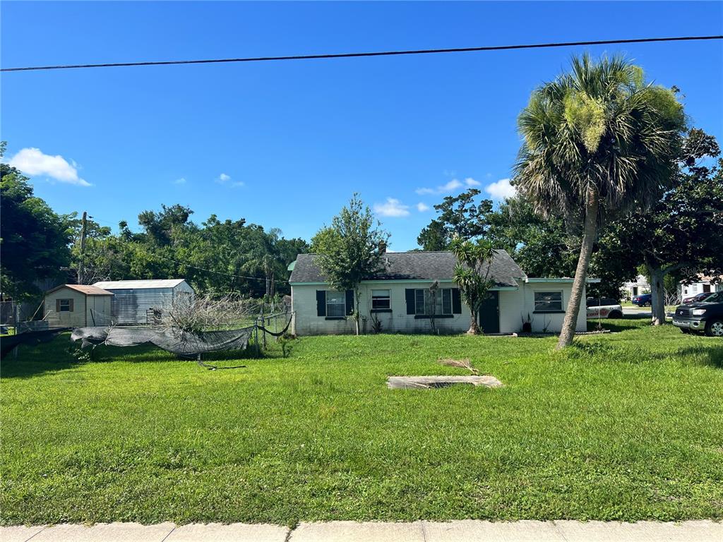 A single-story house with a large front yard, a palm tree, and a detached shed — 104 GRACE AVENUE, COCOA, FL
