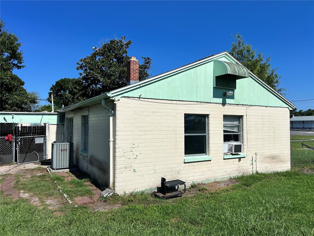 The exterior of a single-story brick building features a green gable and a chimney — 104 GRACE AVENUE, COCOA, FL