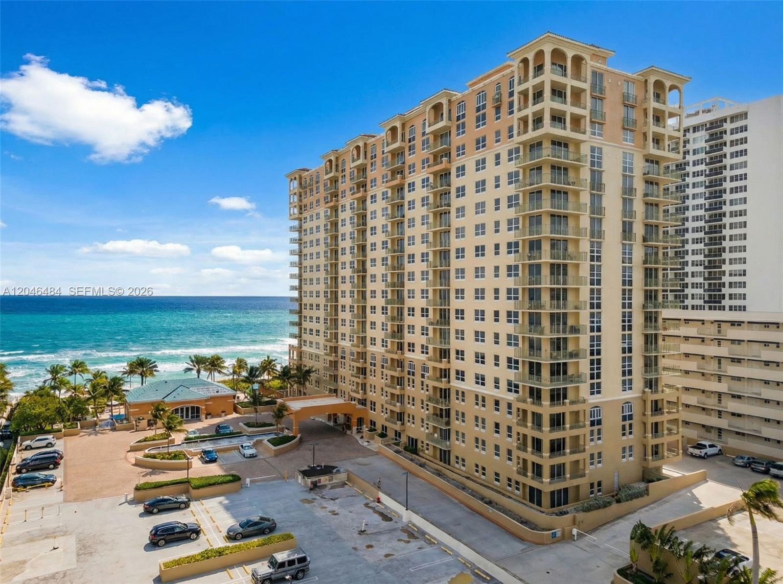 An exterior view of a tall, tan residential high-rise building located next to the ocean — 2080 S Ocean Dr # 1711, Hallandale Beach FL 33009, HALLANDALE BEACH, FL