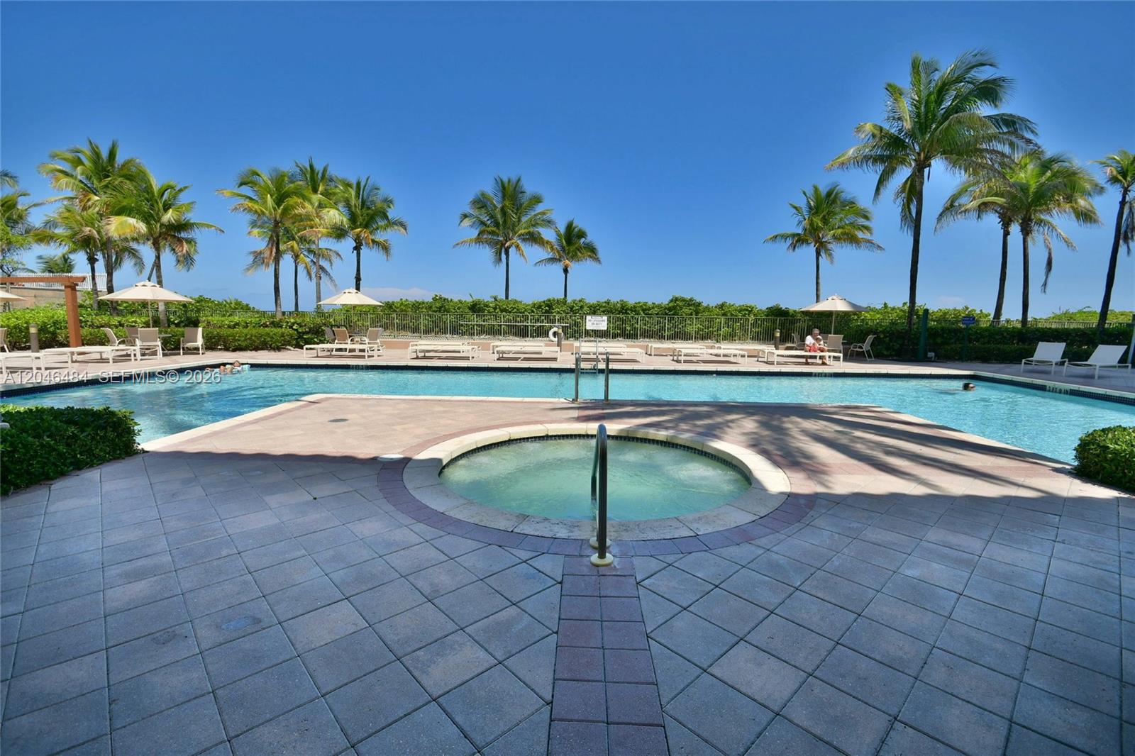 A swimming pool and hot tub are surrounded by a paved deck and palm trees — 2080 S Ocean Dr # 1711, Hallandale Beach FL 33009, HALLANDALE BEACH, FL