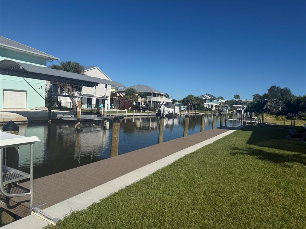 A view of a canal with a boat dock, wooden walkway, and waterfront houses — 10460 RAYMOND STREET, ENGLEWOOD, FL