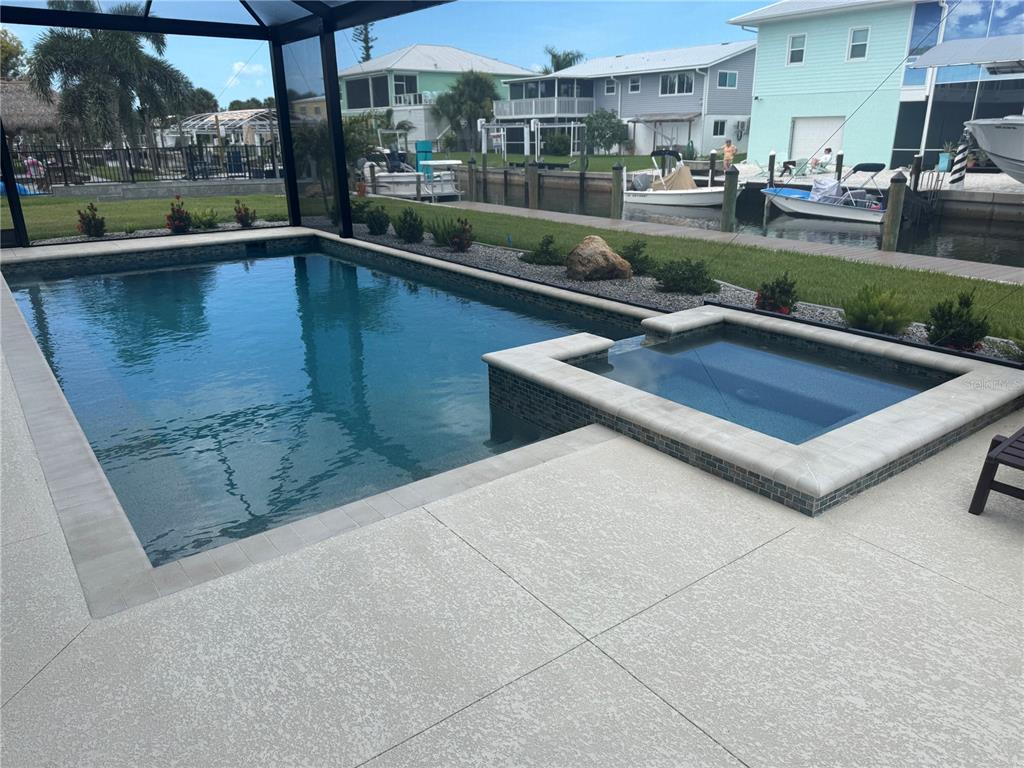 A swimming pool and attached hot tub sit on a patio overlooking a canal — 10460 RAYMOND STREET, ENGLEWOOD, FL