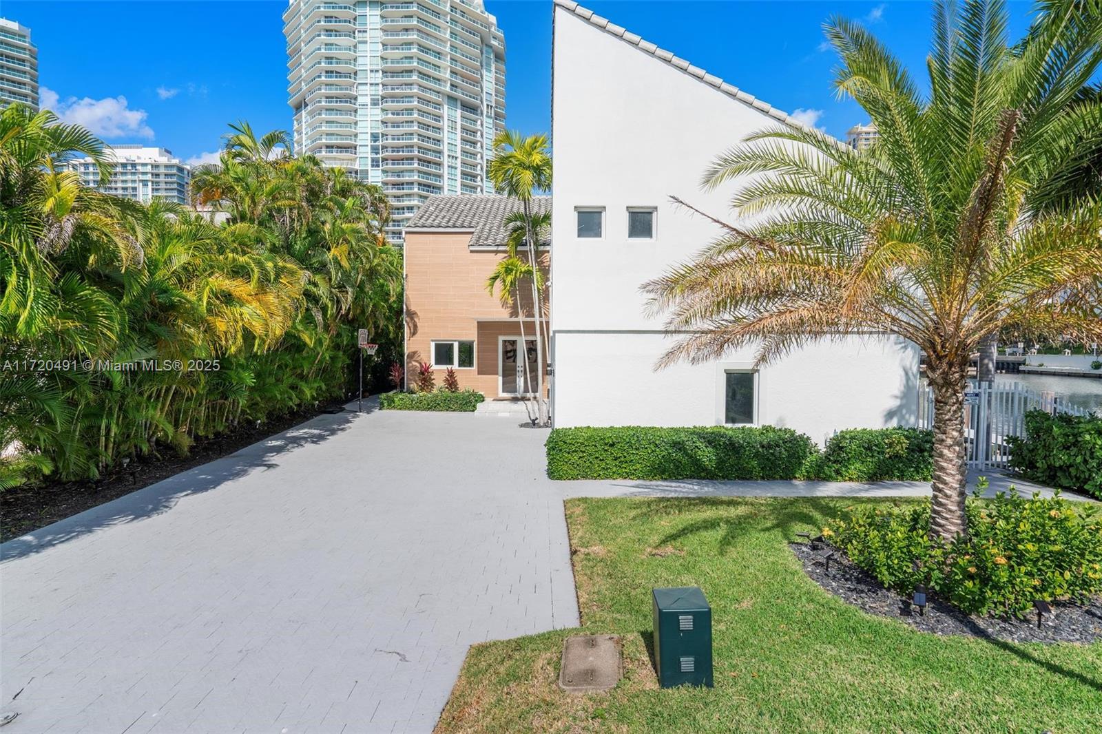 A paved driveway leads to a white house with a tan section and palm trees — 201 Atlantic Ave, Sunny Isles Beach FL 33160, SUNNY ISLES BEACH, FL