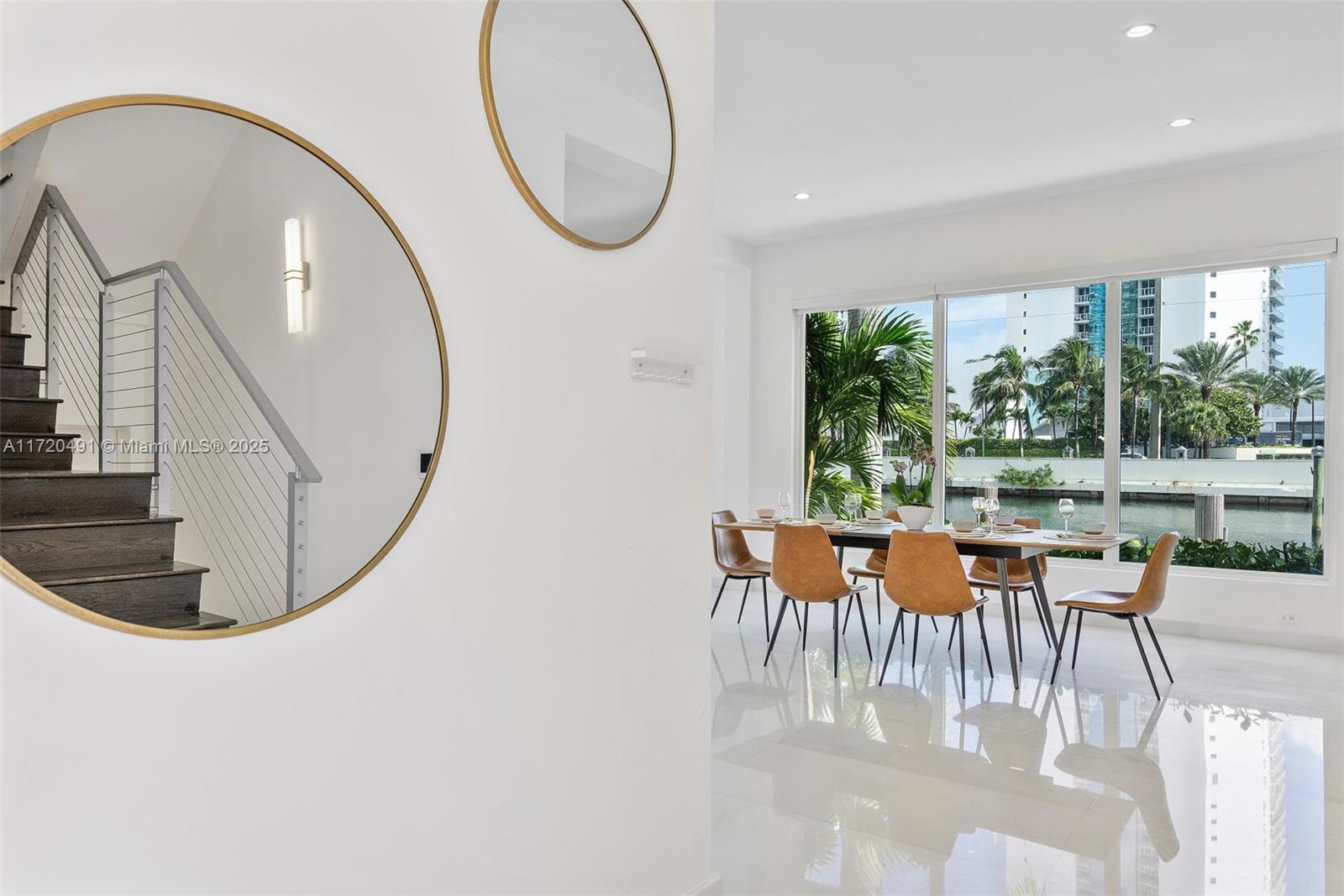A dining area with a table and chairs overlooks a canal through large windows — 201 Atlantic Ave, Sunny Isles Beach FL 33160, SUNNY ISLES BEACH, FL