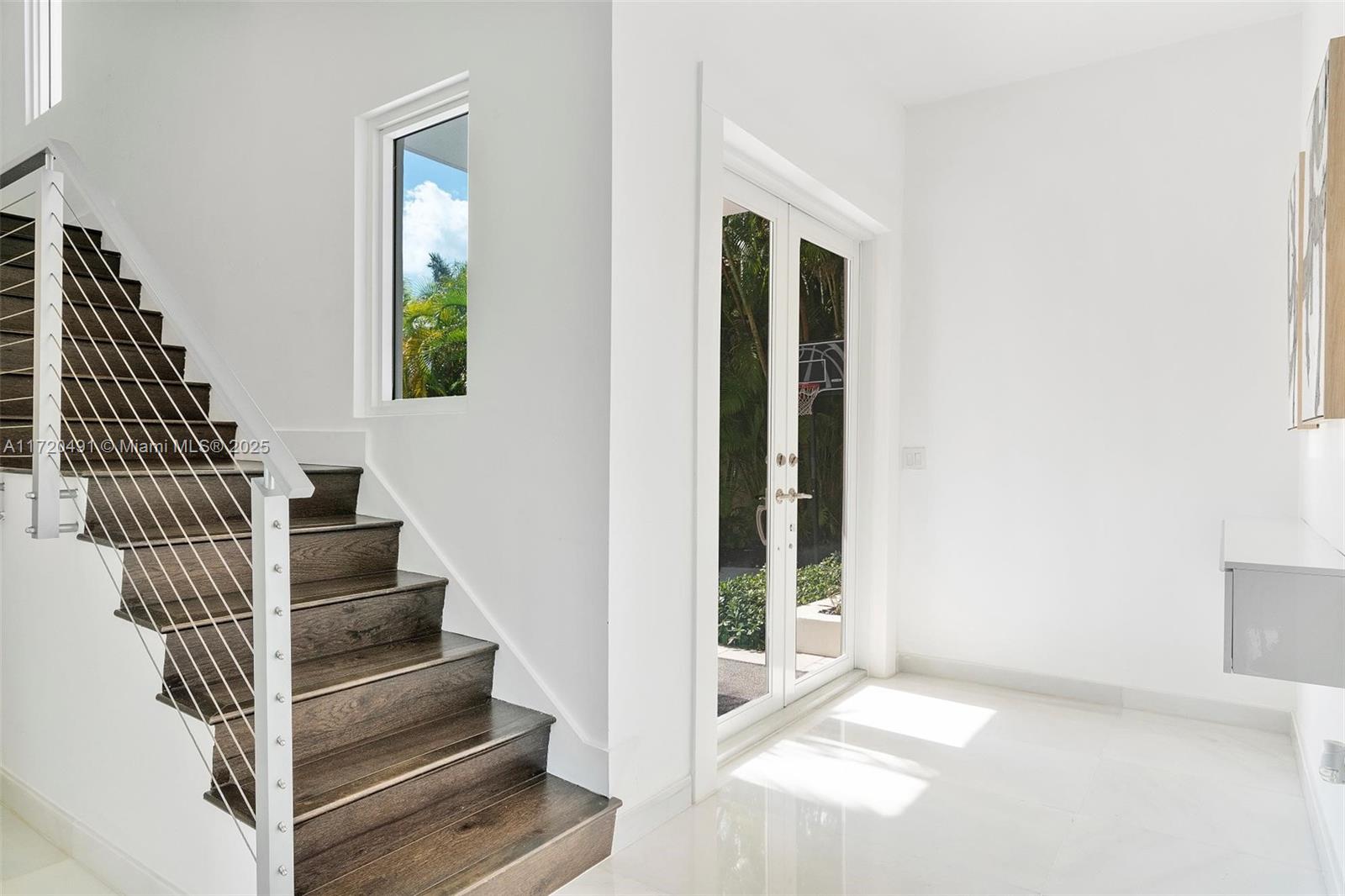A staircase with dark wood treads and a cable railing sits beside a glass door — 201 Atlantic Ave, Sunny Isles Beach FL 33160, SUNNY ISLES BEACH, FL
