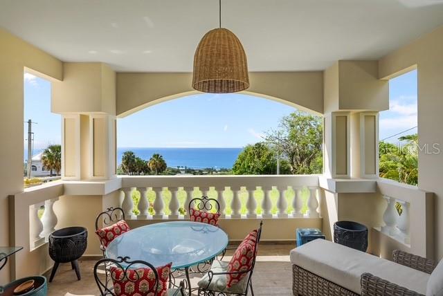 A covered balcony features a dining set, wicker pendant light, and panoramic ocean views — PR 466 ACUAMARINA UNIT KM 4.9, ISABELA, PR