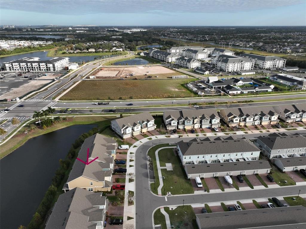 An aerial view shows a residential neighborhood with townhomes, a pond, and nearby commercial development — 6222 CAMINO DRIVE, APOLLO BEACH, FL