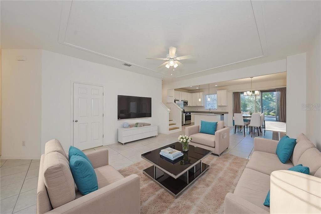 A living room with light tile floors, a white media console, and neutral furniture — 6222 CAMINO DRIVE, APOLLO BEACH, FL