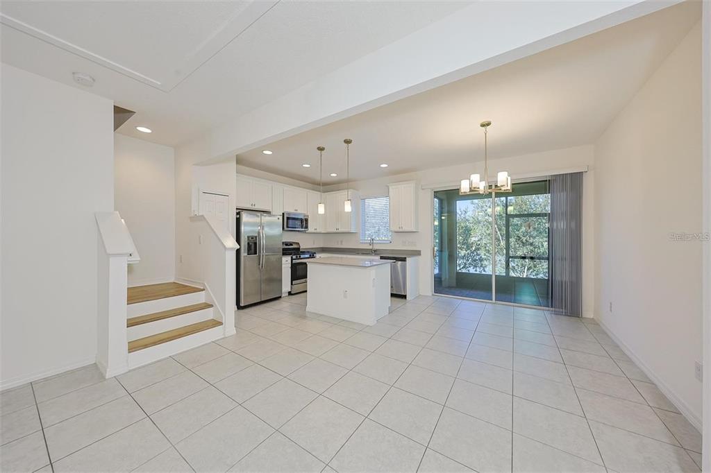 An open-concept kitchen and dining area with white cabinets, stainless appliances, and tile flooring — 6222 CAMINO DRIVE, APOLLO BEACH, FL
