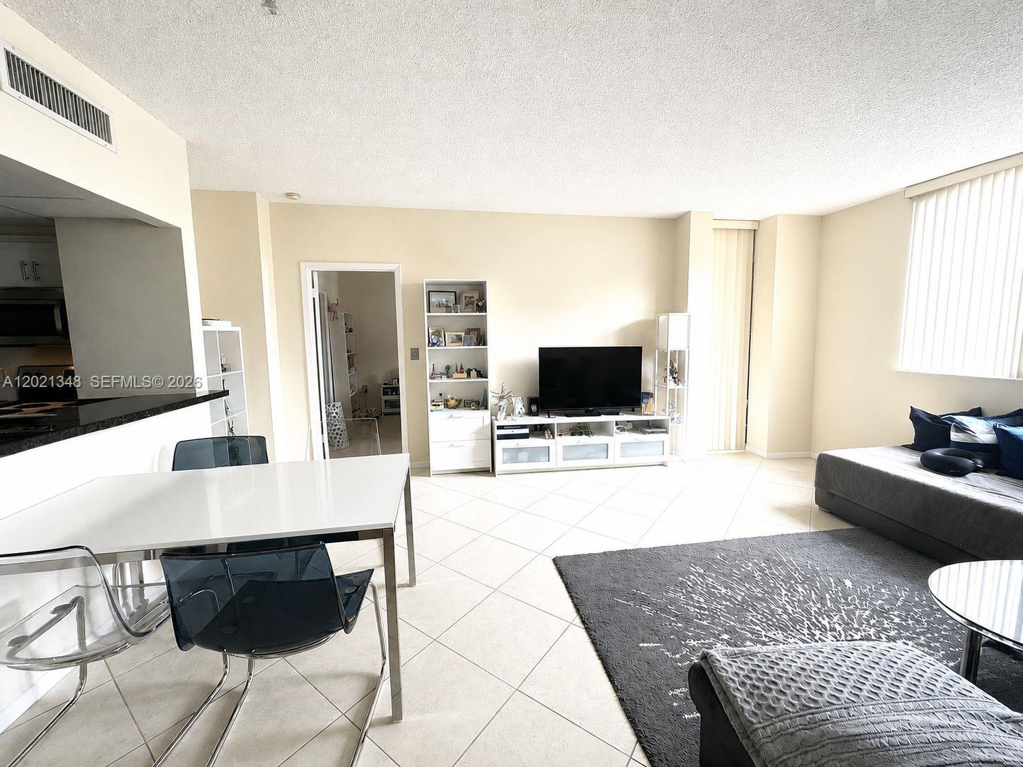 This living and dining area features white tile floors, a television console, and modern furniture — 540 Brickell Key Dr # 1801, Miami FL 33131, MIAMI, FL