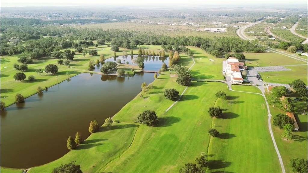 Aerial view of a golf course with a large pond and a clubhouse building — 715 HIBISCUS DRIVE, INDIAN LAKE ESTATES, FL