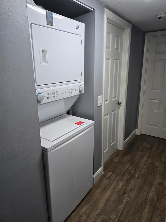 A stacked washer and dryer unit sits in a hallway with gray walls and flooring — 1624 S PINE RIDGE UNIT D2, SANFORD, FL