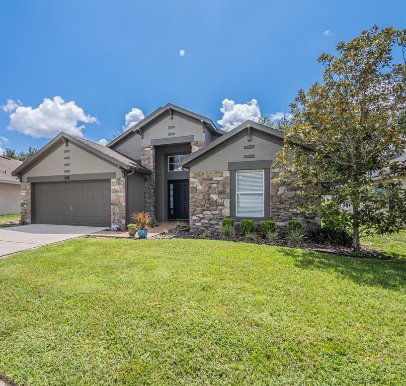 A single-story house with a stone facade, a two-car garage, and a front lawn — 538 WINDSOR ESTATES DRIVE, DAVENPORT, FL