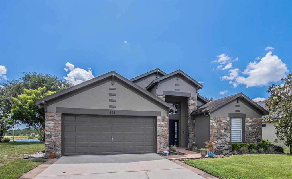 A single-story house with a stone facade, a two-car garage, and a concrete driveway — 538 WINDSOR ESTATES DRIVE, DAVENPORT, FL