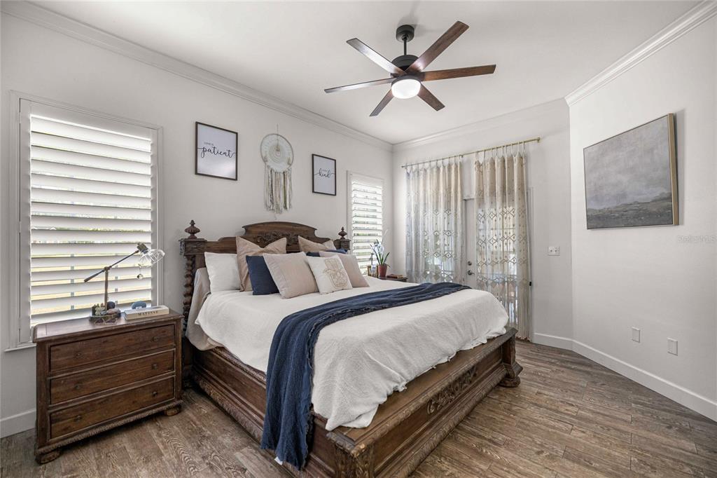 A bedroom features a wooden bed frame, a ceiling fan, and a dresser by a window — 25162 NW 204TH PLACE, HIGH SPRINGS, FL