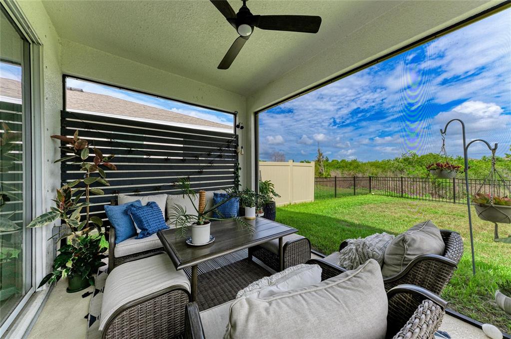 A screened-in patio features wicker furniture, a ceiling fan, and a view of the yard — 10815 CHARLOTTE DRIVE, PARRISH, FL