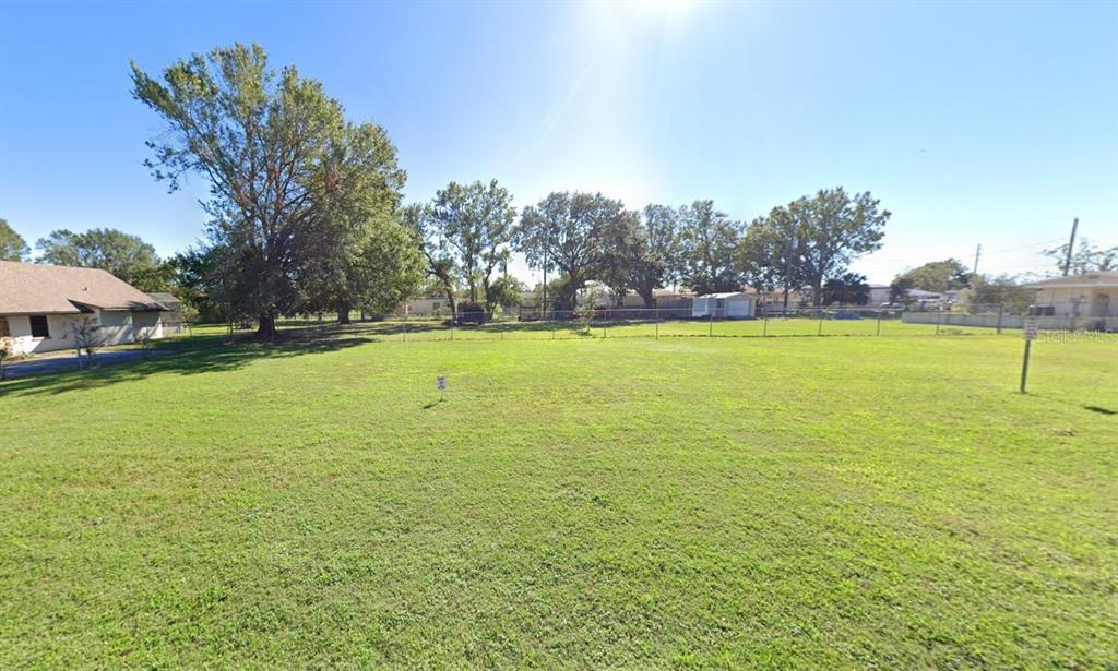 A large, flat, grassy vacant lot is enclosed by a chain-link fence with mature trees — 522 PEARSONS PATH, AUBURNDALE, FL