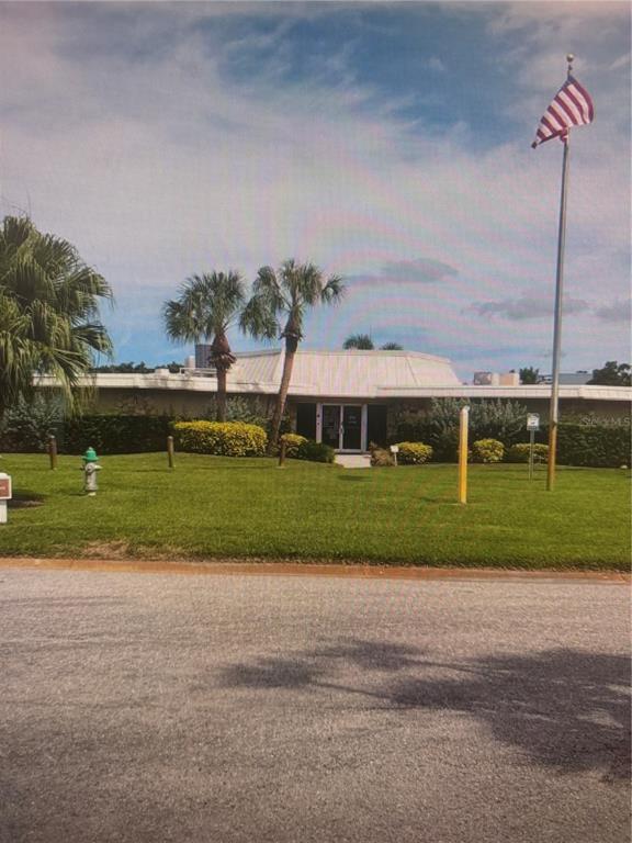A single-story commercial building with a flat roof, palm trees, and an American flag — 4210 IRONWOOD CIRCLE UNIT 404J, BRADENTON, FL