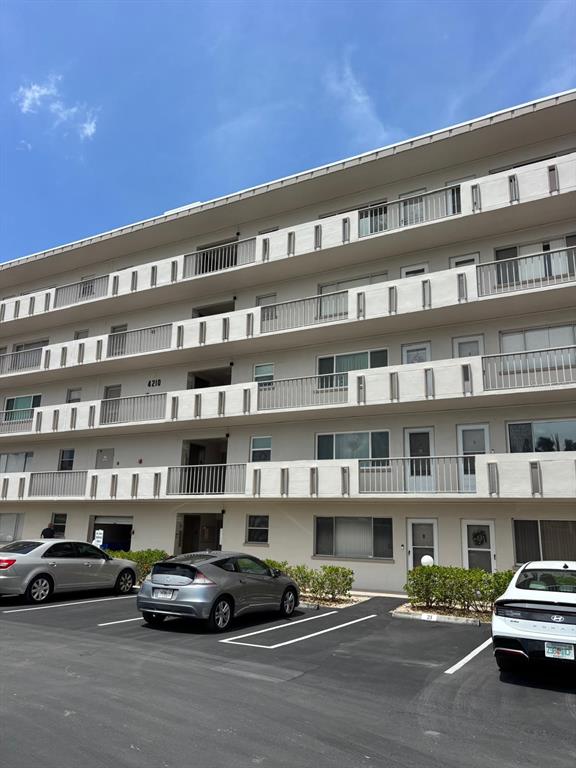 A multi-story apartment building features white exterior walls, balconies, and a paved parking lot — 4210 IRONWOOD CIRCLE UNIT 404J, BRADENTON, FL