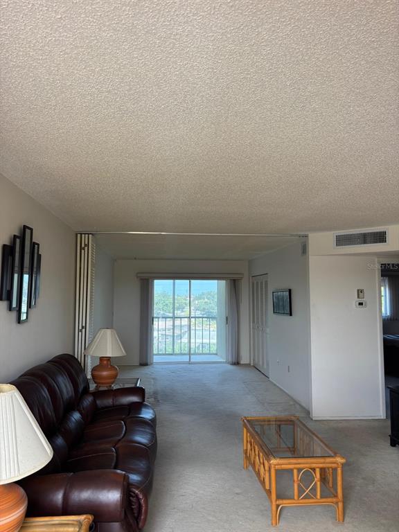 A living room with a brown leather sofa, glass coffee table, and sliding glass balcony doors — 4210 IRONWOOD CIRCLE UNIT 404J, BRADENTON, FL