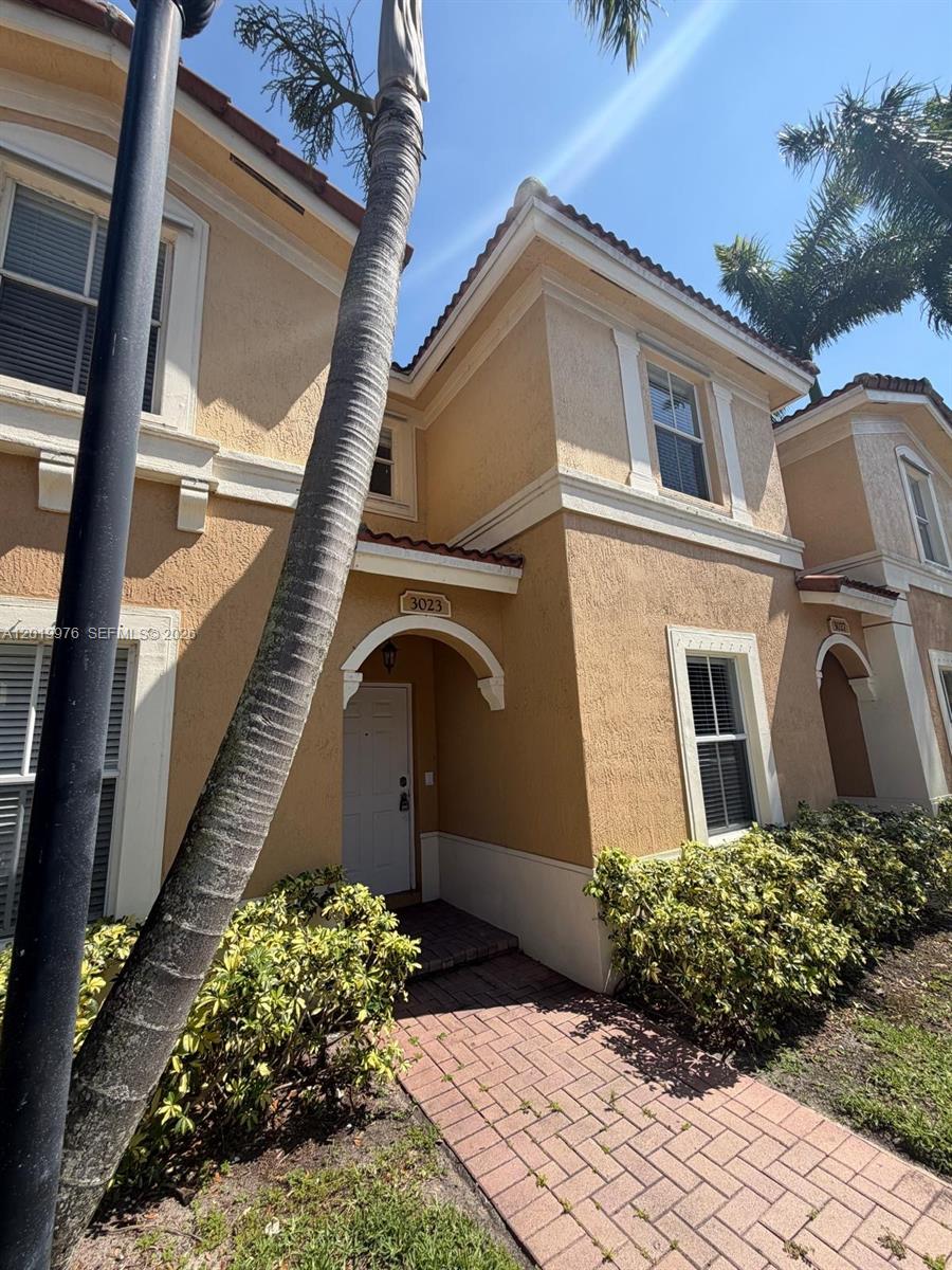 A two-story tan stucco townhouse features a brick walkway leading to a white front door — 3023 SW 129th Ter # 155, Miramar FL 33027, MIRAMAR, FL