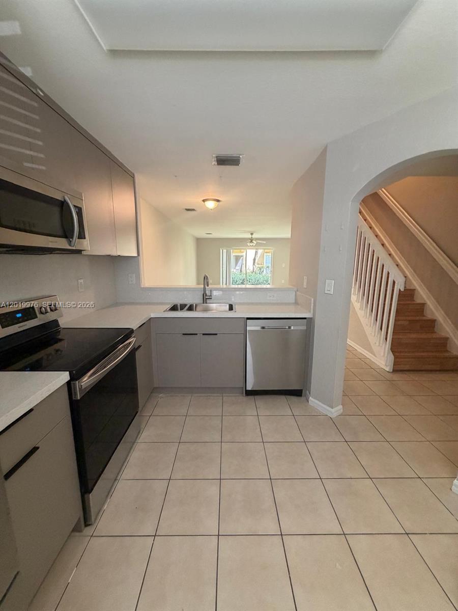 A kitchen features stainless steel appliances, gray cabinets, and a pass-through window to the living area — 3023 SW 129th Ter # 155, Miramar FL 33027, MIRAMAR, FL