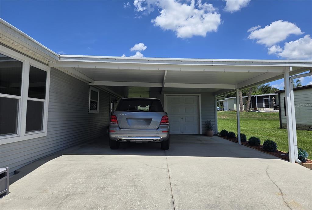A silver SUV is parked under a covered carport attached to a gray-sided house — 3931 COHEN DRIVE UNIT 734, ZELLWOOD, FL