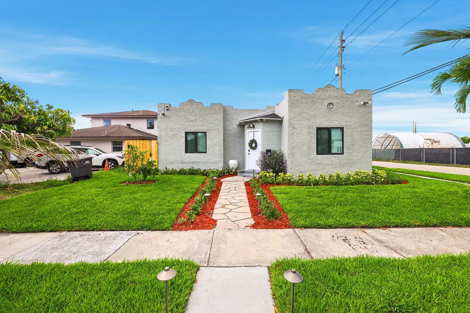 A single-story stucco house with a stone walkway and green lawn under a blue sky — 424 Putnam Road, West Palm Beach FL 33405, WEST PALM BEACH, FL