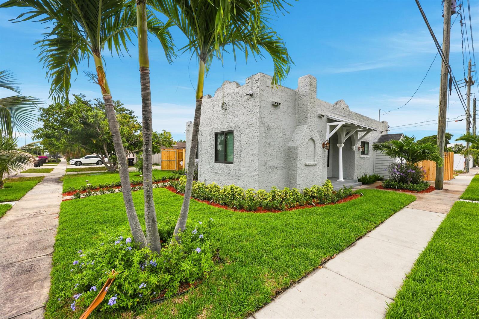 A single-story stucco house with a crenellated roofline sits on a corner lot with palms — 424 Putnam Road, West Palm Beach FL 33405, WEST PALM BEACH, FL