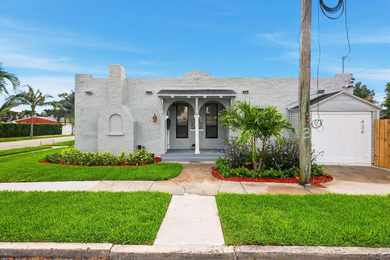 A single-story gray stucco house with a front porch, arched windows, and an attached garage — 424 Putnam Road, West Palm Beach FL 33405, WEST PALM BEACH, FL